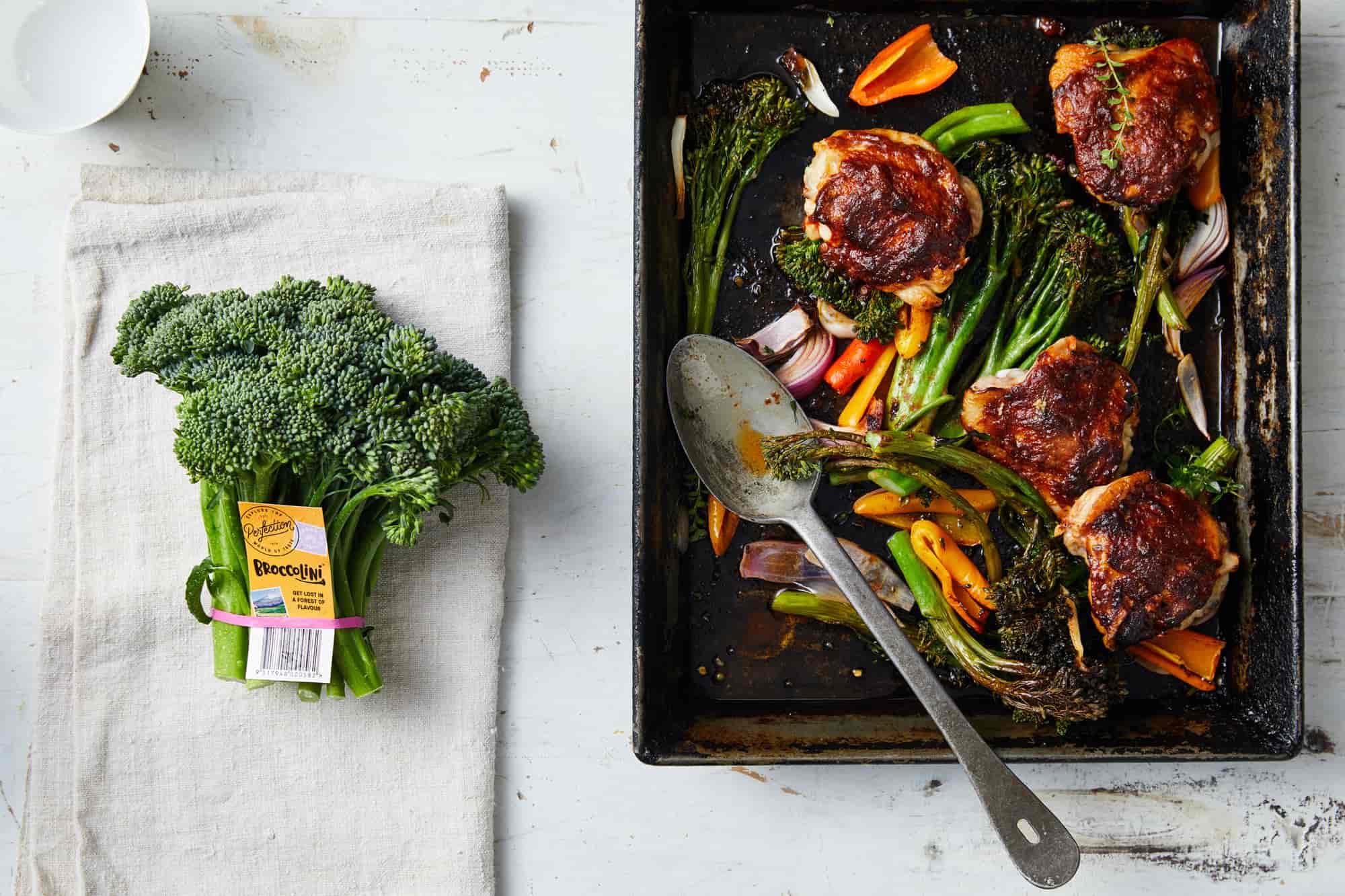 Roasted chicken thigh cutlets with roasted broccolini and other vegetables in a roasting pan.