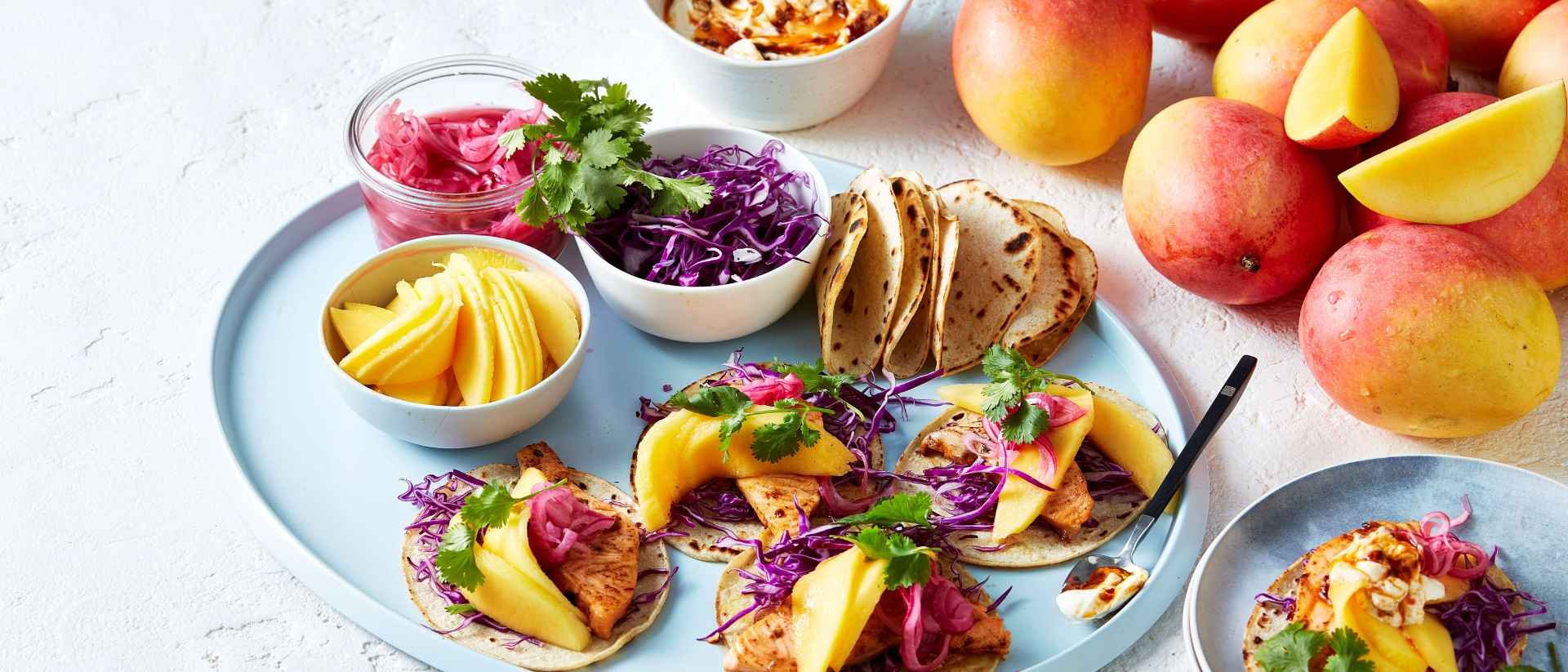 A blue platter with fish tacos with mango, and red cabbage.