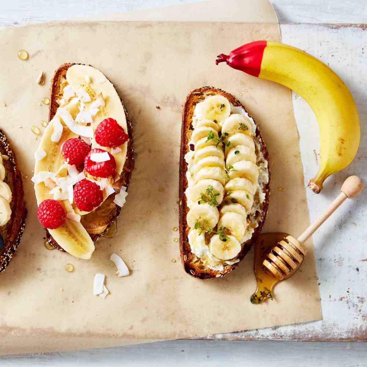 Toast topped with different fruit toppings such as coconut, bananas, honey and raspberries.