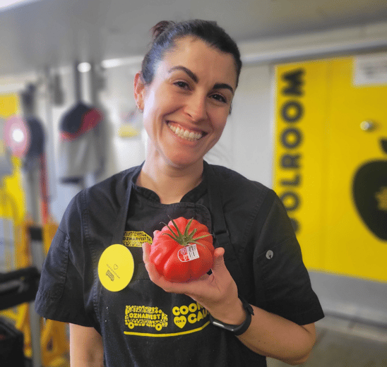 Oz Harvest worker holding Tomato