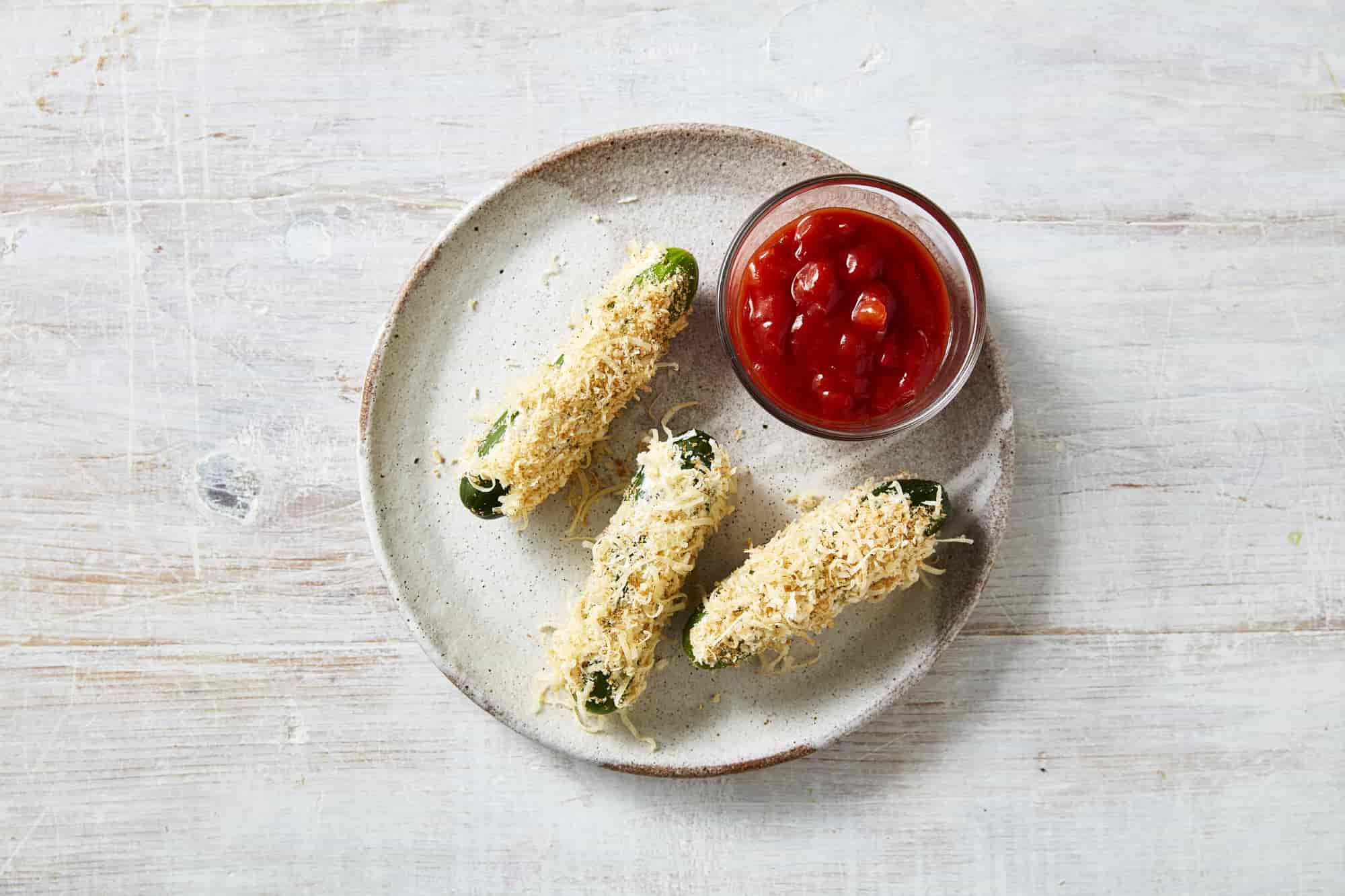 Qukes baby cucumbers rolled in bread crumbs laid out on a plate.