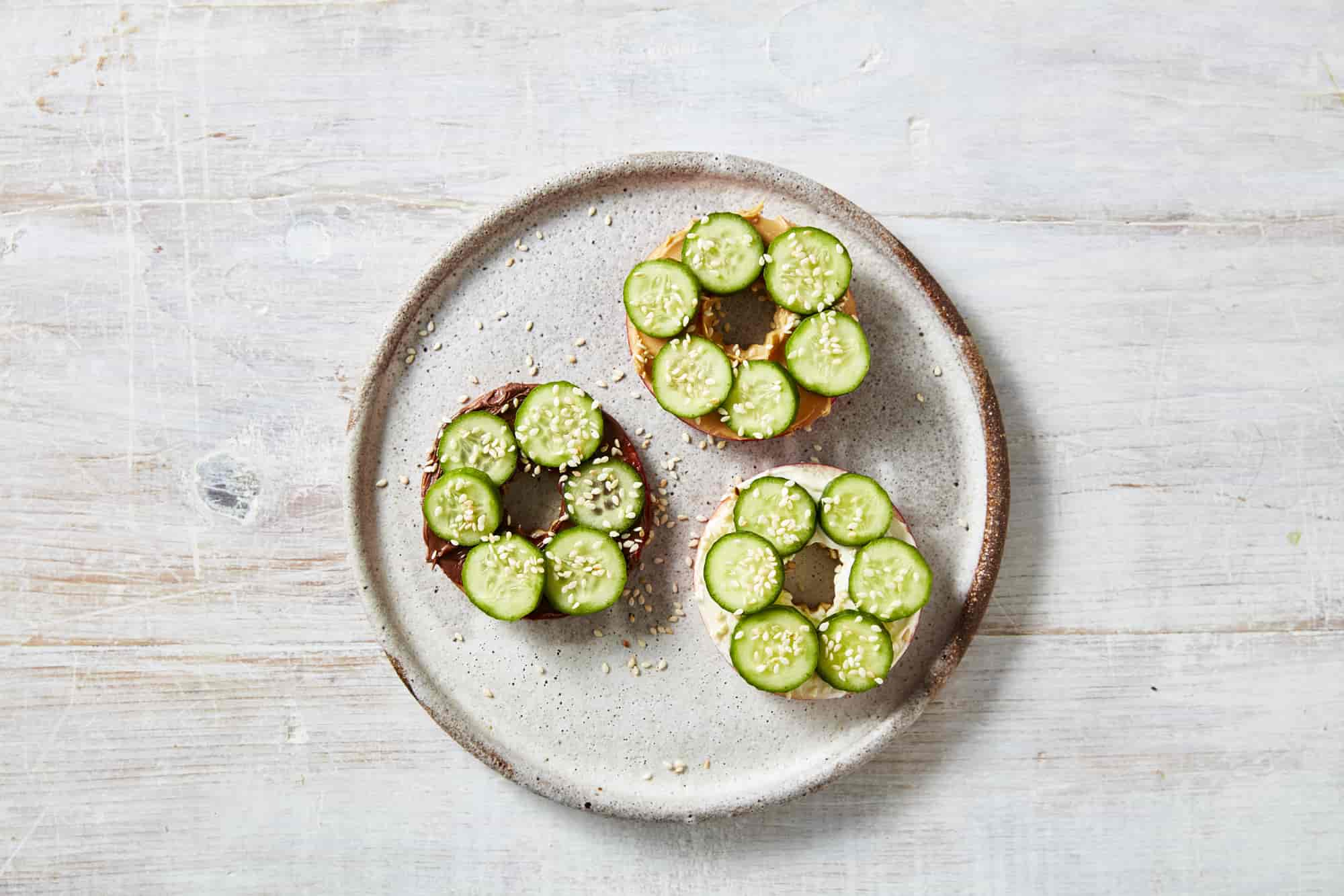 Sliced apple rings topped with sliced Qukes baby cucumbers laid out on a plate.