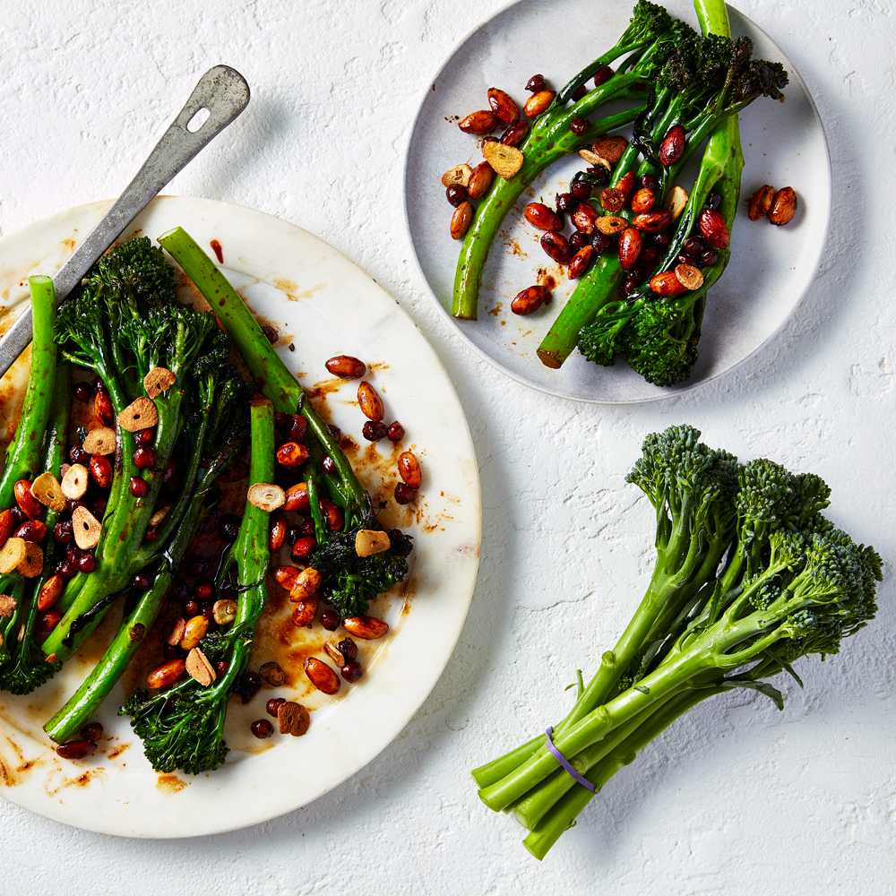Wok fried broccolini with almonds and chickpeas on a platter, with another plate next to it.