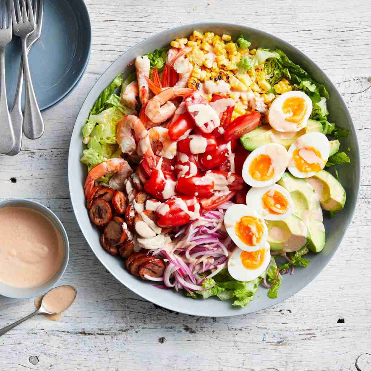 Cobb salad with boiled eggs, avovado, onions, olives, prawns and romatherapy tomatoes on a bed of lettuce.