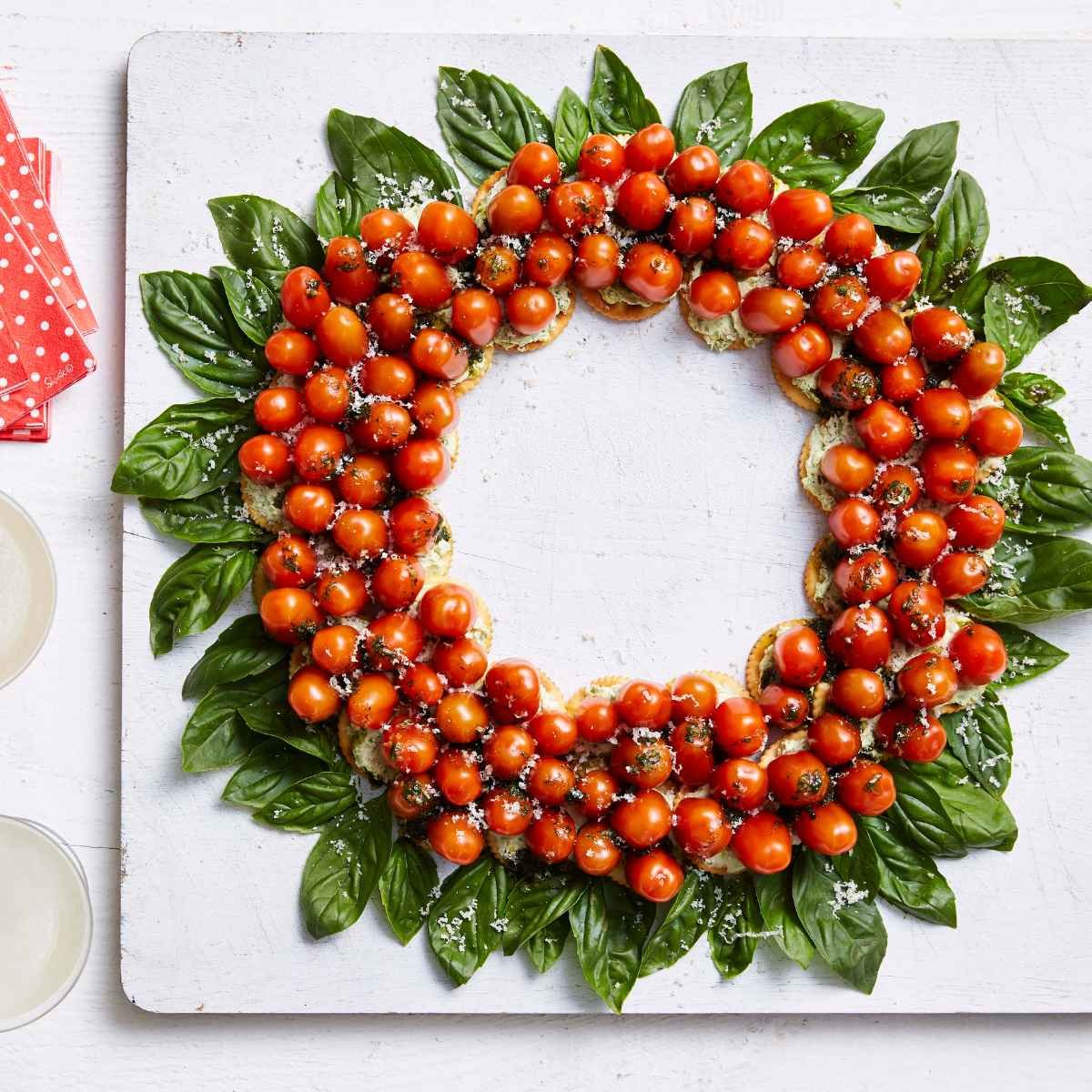 A tomato and basil wreath on a white board.