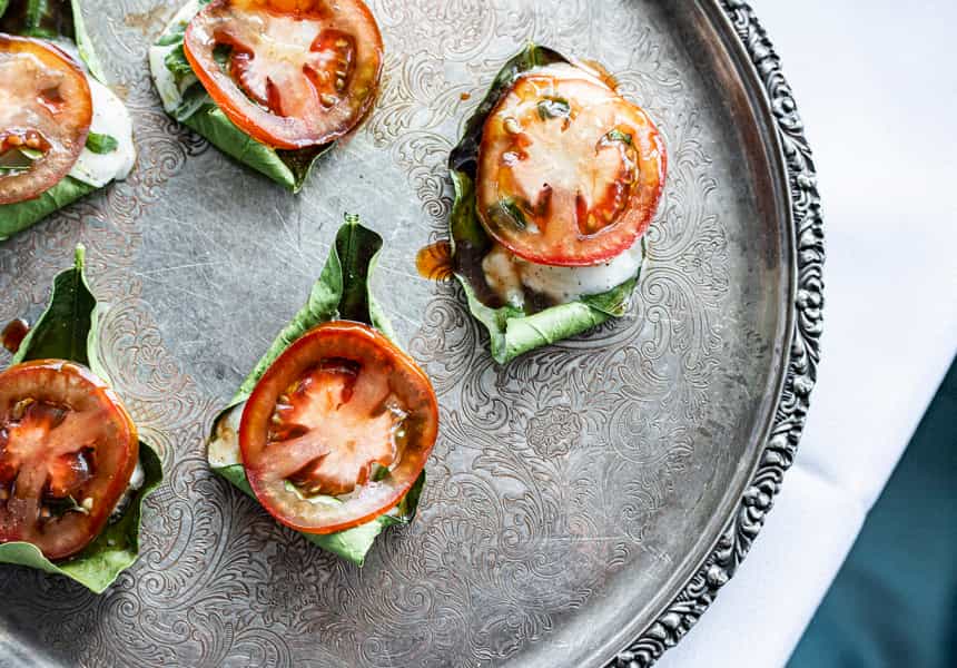 Mini canapes with Kumato tomatoes on a silver plate.