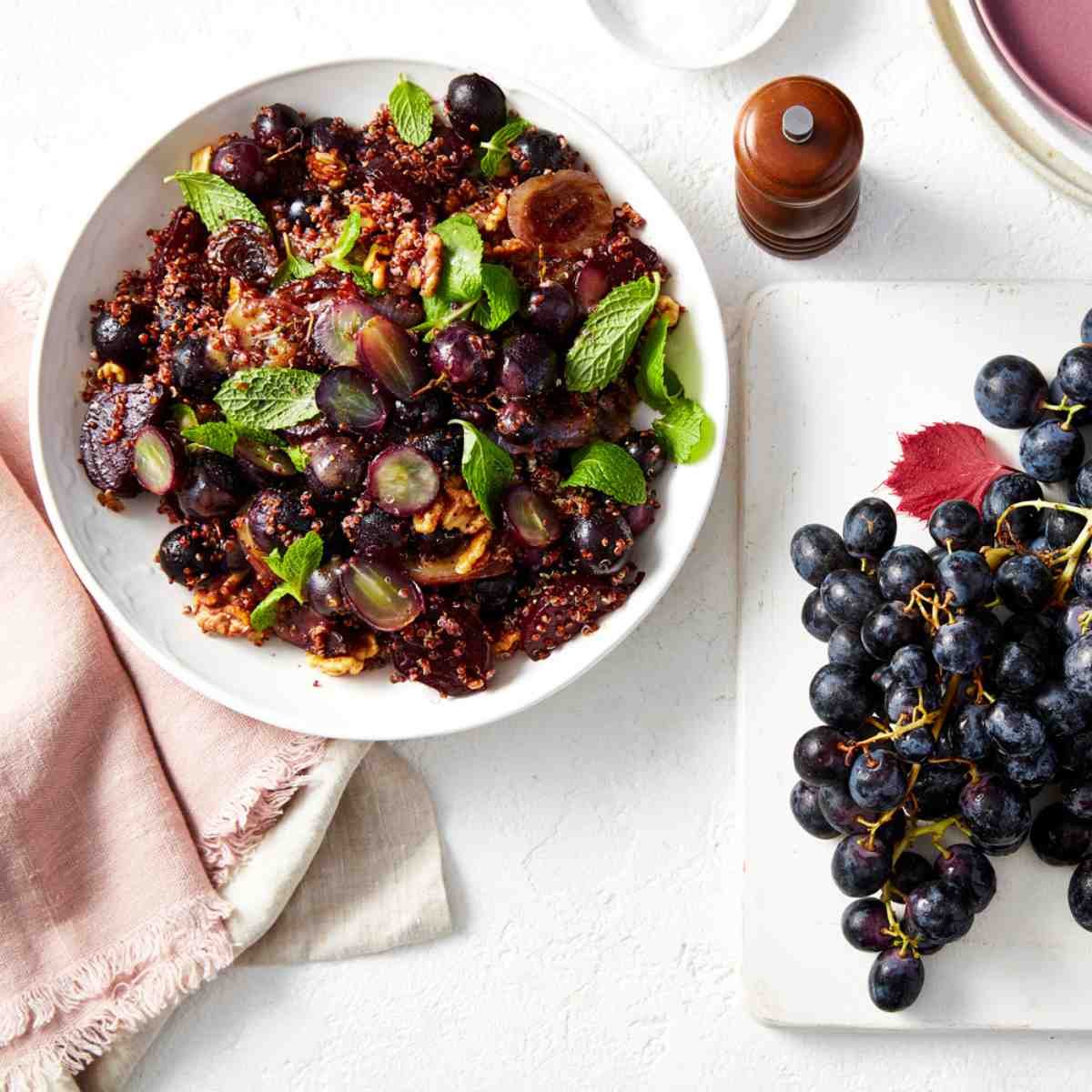 A bowl of grape salad with walnuts, quinoa and mint.