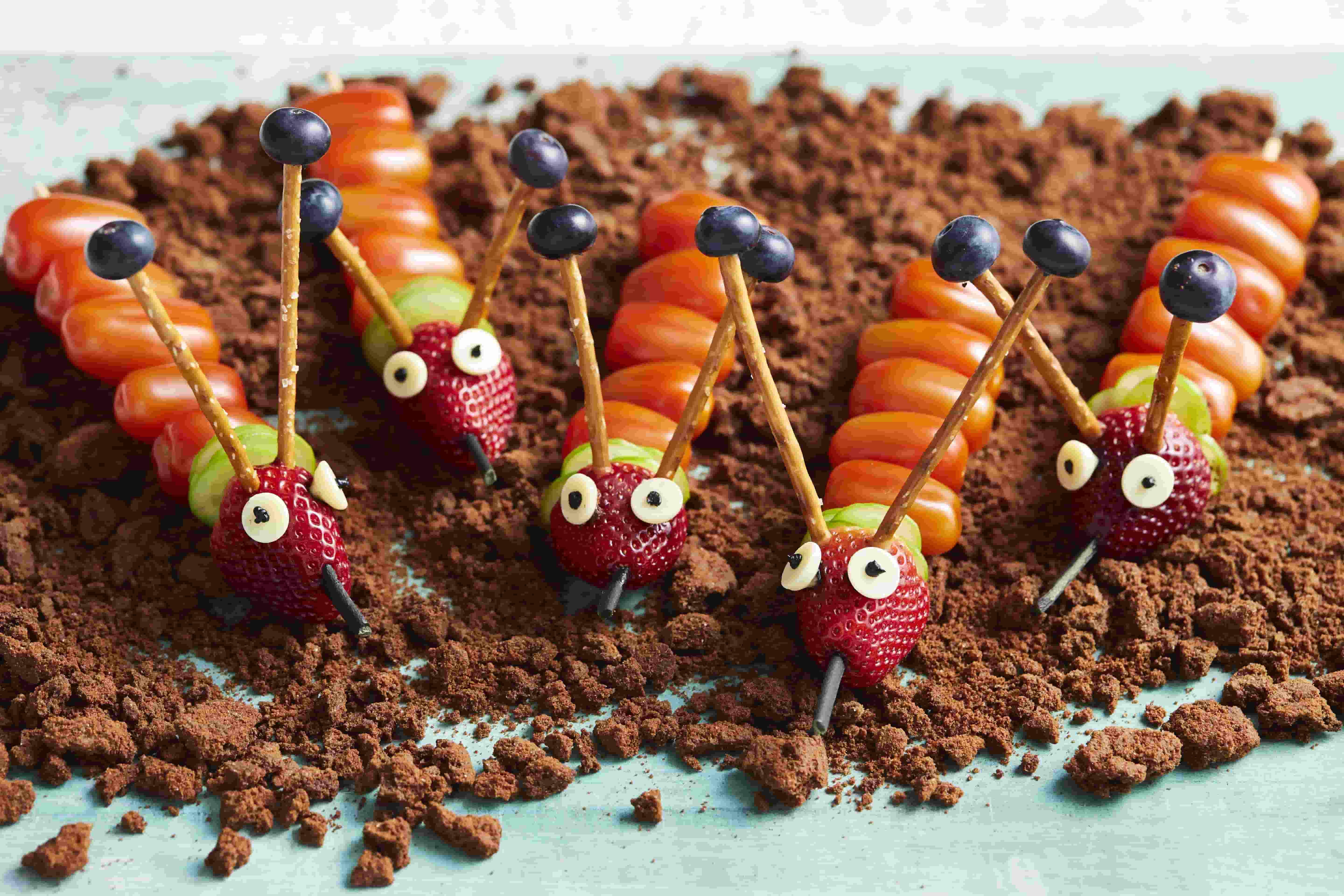 Edible caterpillars made out of strawberries, blueberries, tomatoes, and cucumbers.